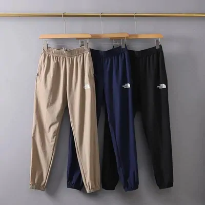 Tres pantalones de chándal en beige, azul marino y negro colgados de una barra