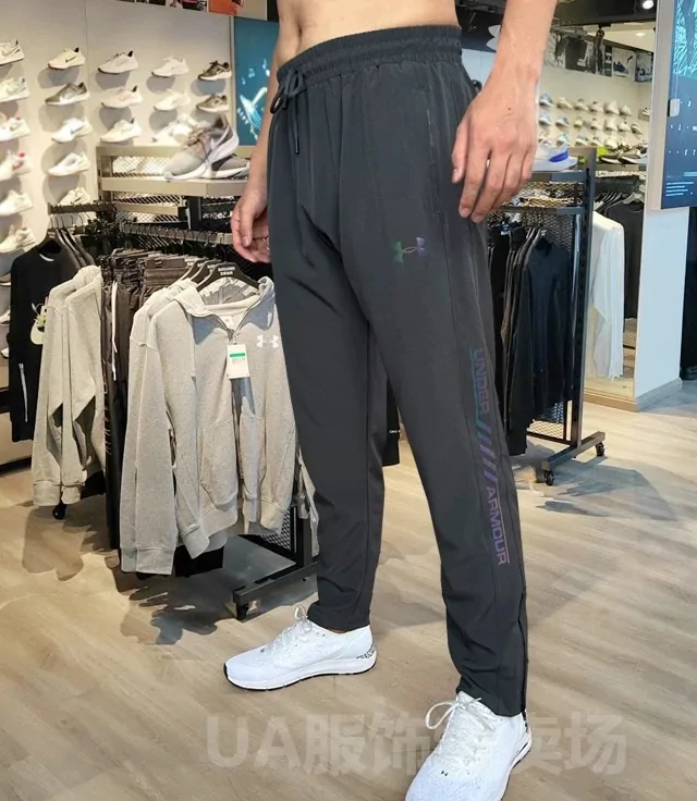 Persona con un pantalón de chándal gris oscuro y zapatillas blancas de pie en una tienda de ropa deportiva